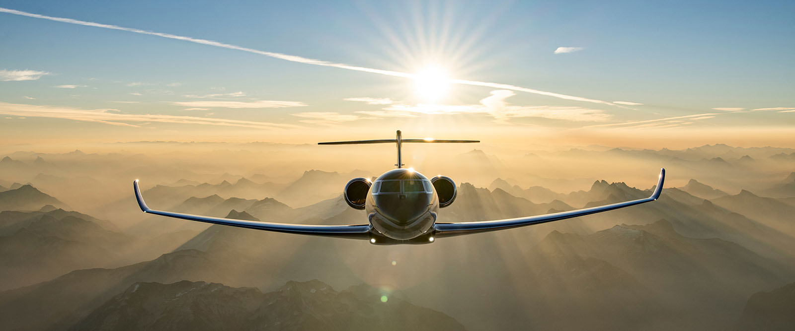 Cloud tops glow in low-angle sunlight below a G700 in flight