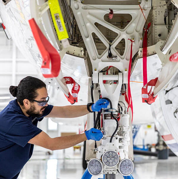 A Gulfstream Customer Support employee services landing gear on an aircraft.