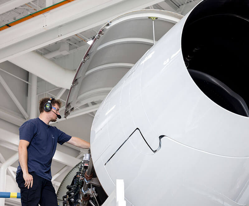 A Gulfstream Customer Support employee services an engine of a Gulfstream aircraft in a service hangar..