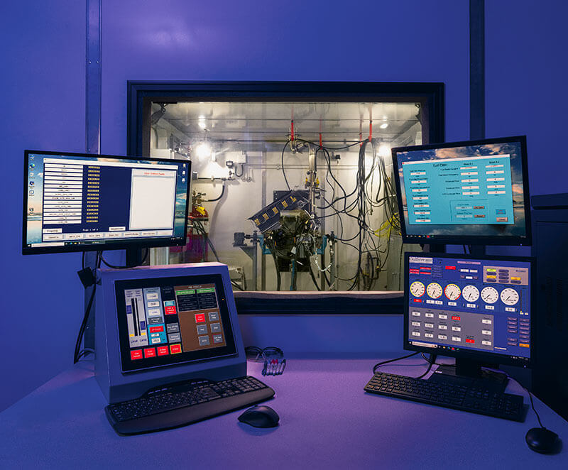 Monitors surround an observation window looking into a Gulfstream APU Services repair bay.