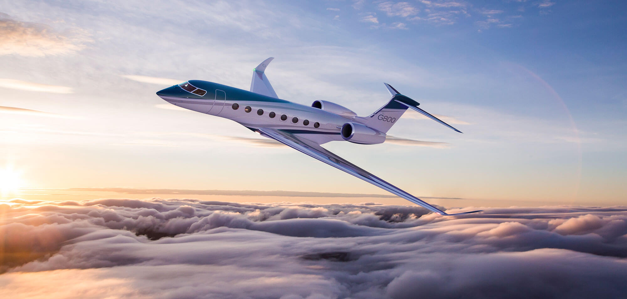 A Gulfstream G800 soars above clouds lit by a sunrise.