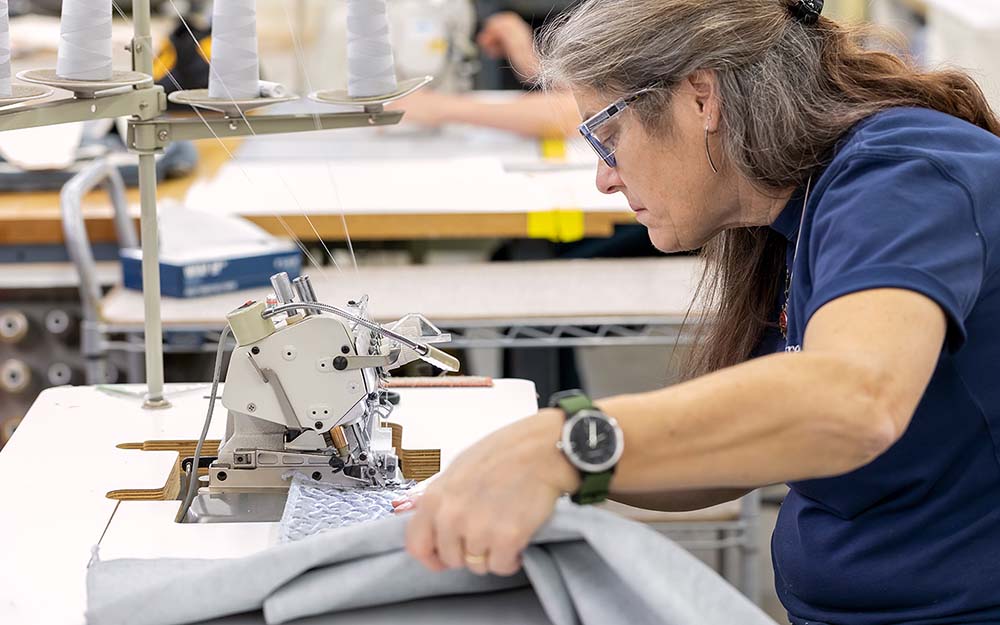 An employee focuses intently on material she is stitching.