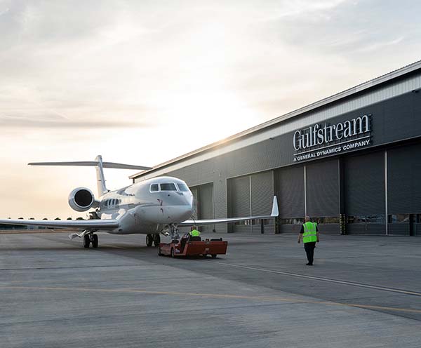 Employees at Gulfstream's Farnborough Service Center tow an aircraft twoard a service hanger.