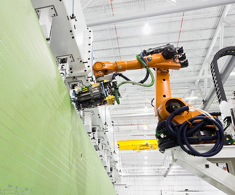 An orange robotic arm performs assembly work on a Gulfstream aircraft in Savannah, Georgia.